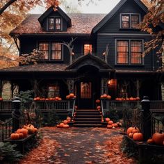 a black house with lots of pumpkins on the front porch