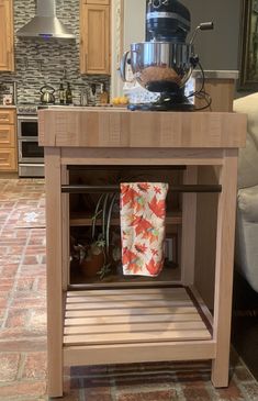 a kitchen island with an open shelf on the side and a coffee pot on top