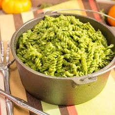 a bowl filled with green food on top of a table next to utensils