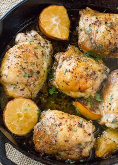 chicken and oranges cooking in a cast iron skillet