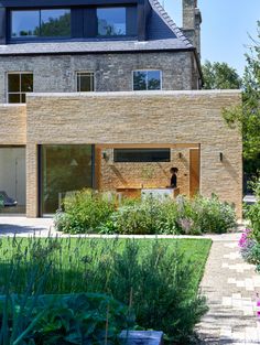 the house is made out of bricks and has an open front yard with lots of greenery