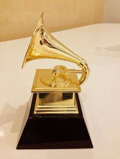 an old fashioned golden record player on a white table with a gold horn and black base