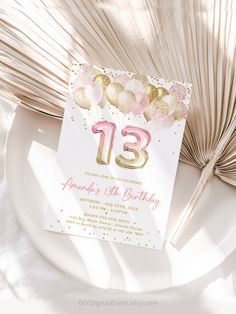 a white plate topped with a pink and gold 21st birthday party card next to a fan