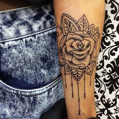 a woman's arm with a rose tattoo on the forearm and an intricate design