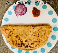 an aloo paneer paratha on a plate with onions and garlic