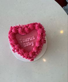 a heart shaped cake with the words taurus baby written in pink frosting on it