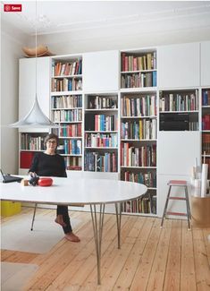 a person sitting at a table in front of a book shelf with books on it