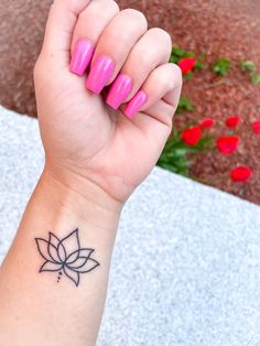 a woman's wrist with a lotus tattoo on the left side of her arm