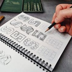 a person holding a pencil while drawing letters