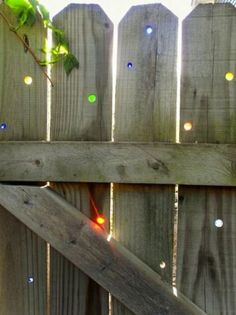 a wooden fence with lights on it and a tree branch in the middle of the fence