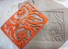 an orange and gray cutting board sitting on top of snow covered ground with cut outs