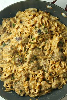 a skillet filled with pasta and meatballs