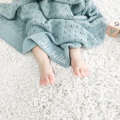 a baby wrapped in a blue blanket laying on the floor next to a wooden block