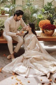 a man and woman are sitting on a bench in front of flowers with petals all over the floor