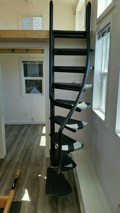 there is a spiral staircase in the middle of a room with wood flooring and white walls