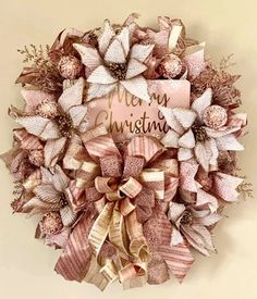 a christmas wreath with pink and gold bows on it that says merry christmas written on the front