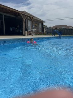 a child swimming in a blue pool next to a house