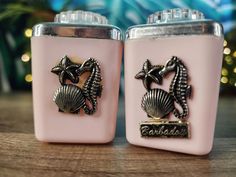 two pink salt and pepper shakers with seahorses on the front one is silver