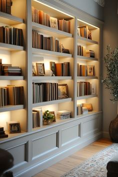 a living room filled with lots of white bookshelves next to a vase full of flowers