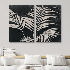 two black and white paintings hanging on the wall above a couch in a living room