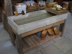 a concrete sink sitting on top of a wooden table next to baskets and boxes filled with bananas