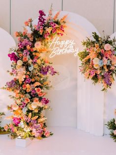 an arch decorated with flowers and happy birthday written on it