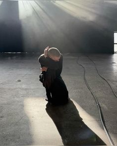 a person sitting on the ground with their hands up in the air and sunlight streaming through them