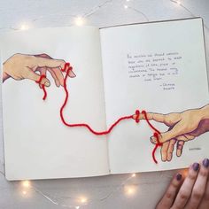 an open book with two hands and string attached to it