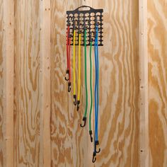 a bunch of umbrellas hanging from the side of a wooden wall with strings attached to them