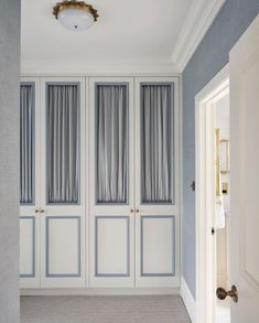 an empty room with blue walls and white closets in the corner, along with a light fixture on the ceiling