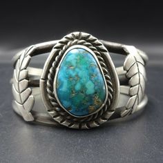 "VINTAGE NAVAJO BRACELET DESCRIPTION: This classic vintage Navajo cuff features a glorious specimen of medium to deep blue-green turquoise. The gemstone is secure in smooth bezel, on a foundation of heavy gauge vintage sterling silver. Applied leaves flank the turquoise cabochon. This bracelet will be a cherished addition to your collection of fine vintage Native American jewelry. MEASUREMENTS: Interior of the cuff measures 5 1/4\" with an additional 1 1/4\" slightly adjustable gap. Total circum Classic Adjustable Turquoise Cuff Bracelet, Vintage Adjustable Gemstone Cuff Bracelet, Adjustable Vintage Gemstone Cuff Bracelet, Blue Oval Vintage Cuff Bracelet, Classic Adjustable Turquoise Ring, Vintage Gemstone Cuff Bracelet Collectible, Classic Turquoise Cuff Bracelet Gift, Vintage Sterling Silver Cuff Bracelet With Patina, Bones Bracelet