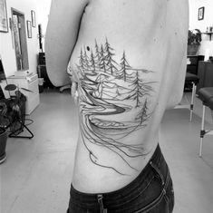 a man with a tattoo on his back that has trees and mountains in the background