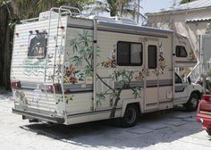 an rv parked in front of a house with palm trees and flowers painted on it