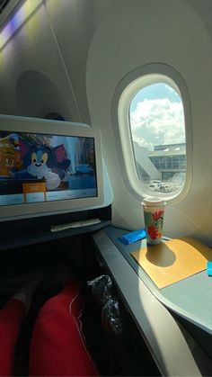 the view from inside an airplane window looking out at a cartoon character holding a cup