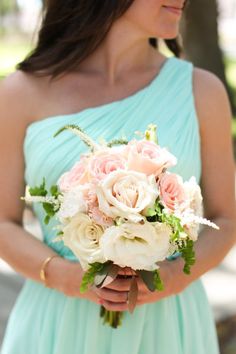 a woman in a blue dress holding a bouquet of white and pink flowers on her wedding day