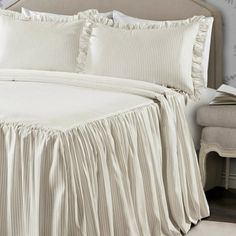 a white bed with ruffled bedspread and pillow cases on top of it