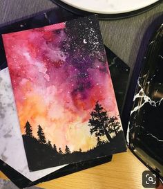 two cards with watercolors on them sitting on a table