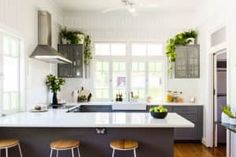 a kitchen with three stools in front of the counter and an island that has plants on it