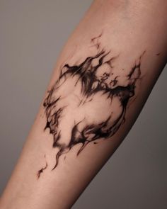 a black and white photo of a tattoo on someone's arm with ink swirling around it