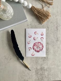 a card with an ink pen on it next to some flowers and other items that include feathers