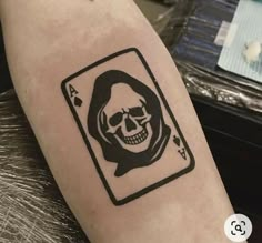 a skull in a card tattoo on the arm