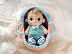 a small crocheted doll in a blue and pink basket with white laces