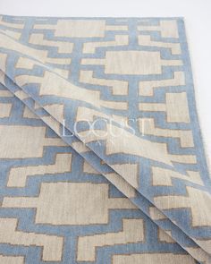 a blue and beige area rug with an interlocked design on the bottom side