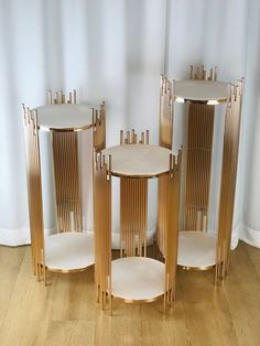 three gold and white side tables sitting on top of a hard wood floor next to a curtain