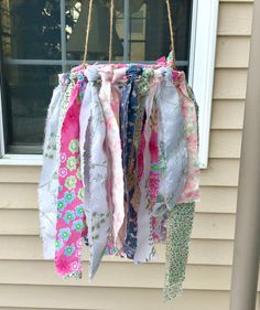 several different colored scarves hanging from a window sill in front of a house