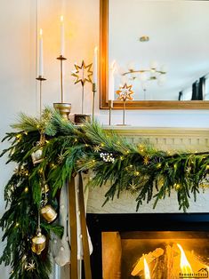 a fireplace decorated for christmas with garland and candles on it's mantle, next to a mirror