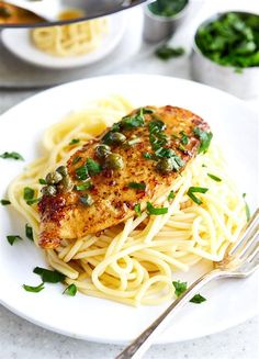 a white plate topped with pasta and meat covered in green onions on top of a table