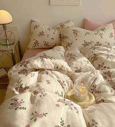 an unmade bed with flowers on it and a candle in the middle, next to a night stand