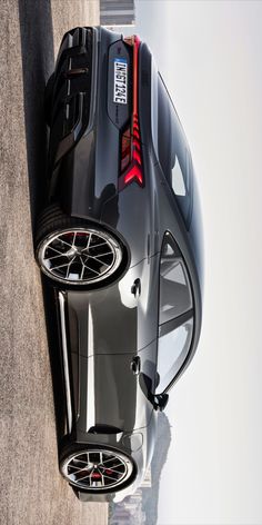 the rear end of a black sports car with its hood up and wheels down, seen from above