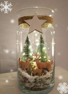 a glass jar filled with fake trees and deer under a snowflaked star